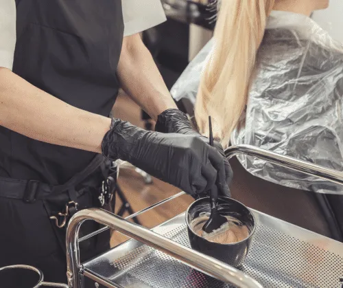 Hairstylist mixing hair color in a bowl.